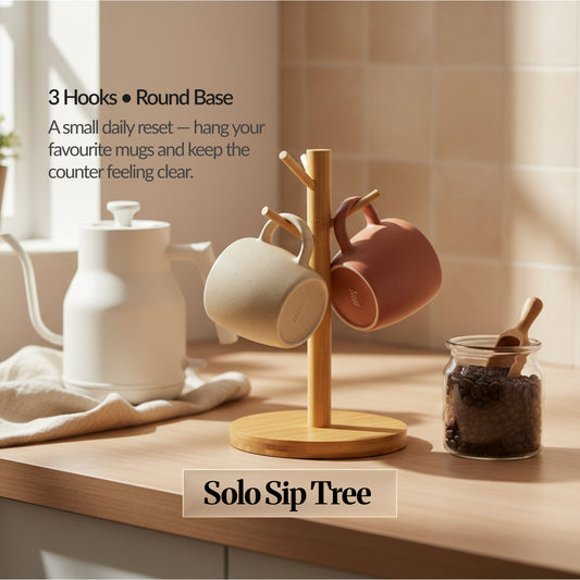 Solo Sip Tree variant: small bamboo mug tree with 3 hooks on a round base holding two mugs, styled on a bright kitchen counter for minimal daily use.