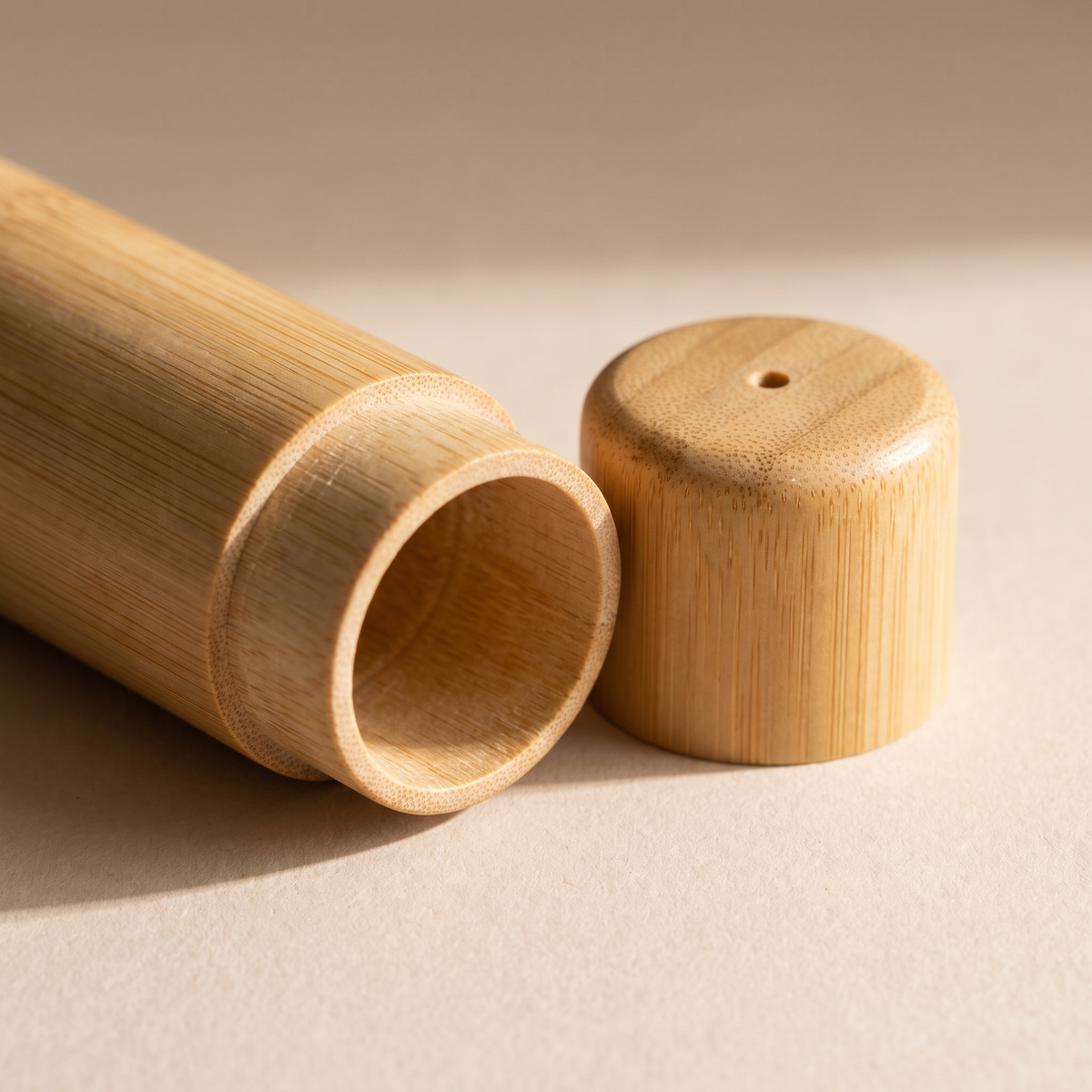 Close-up of the open bamboo tube beside its cap, showing the bamboo grain