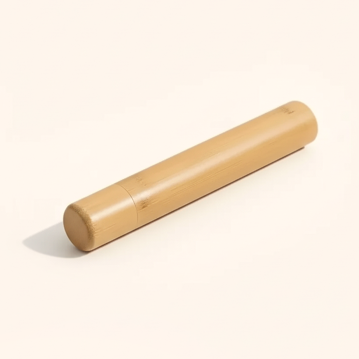 The closed bamboo toothbrush case lying on its side on a cream background