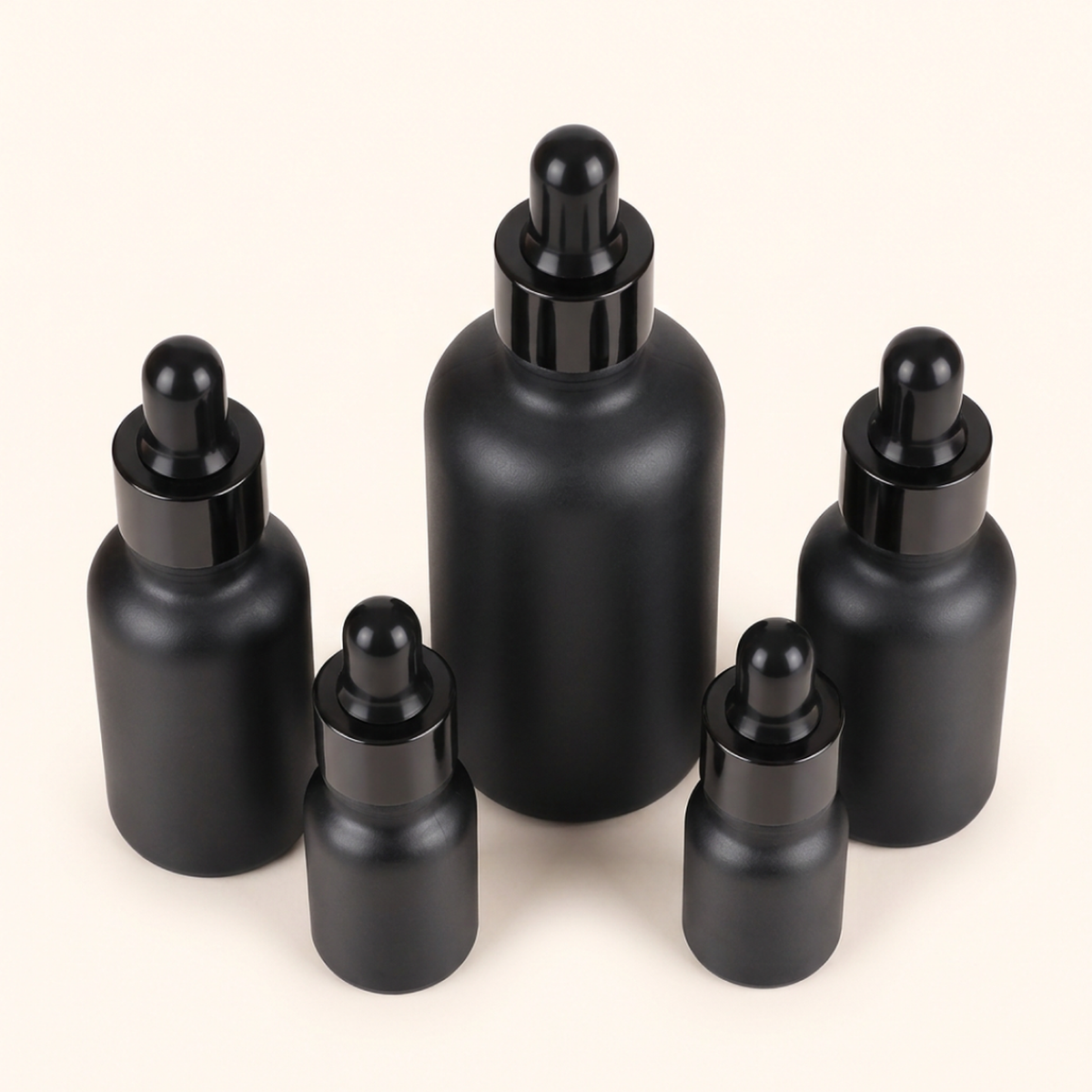 Five black dropper bottles of different heights arranged together