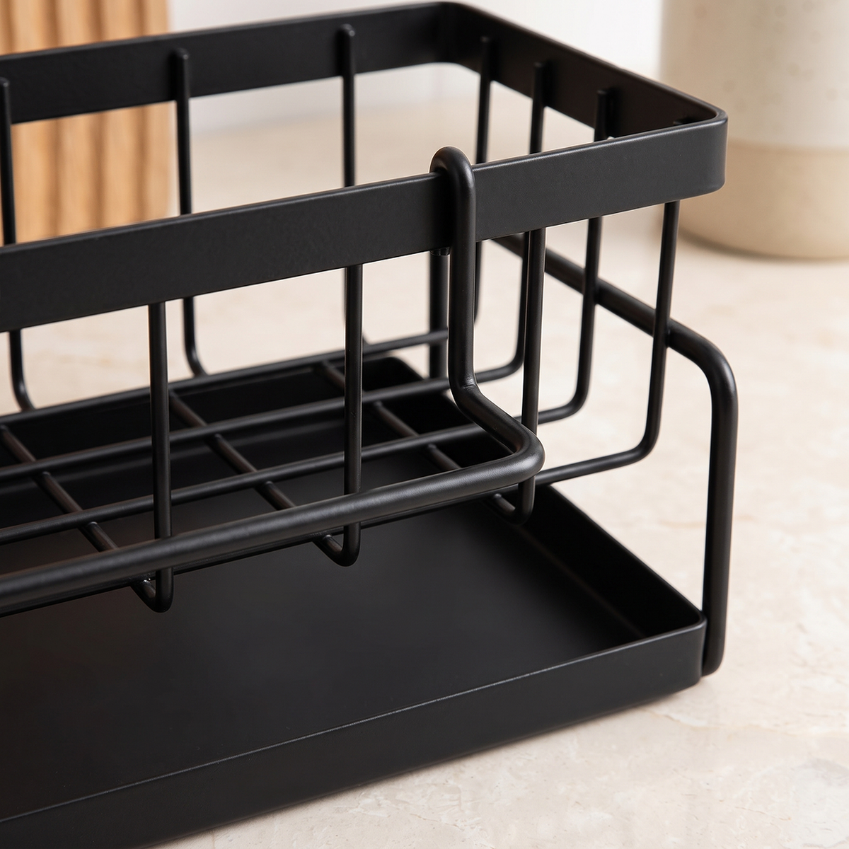 Close-up of the black wire basket, its front bar and the solid tray below