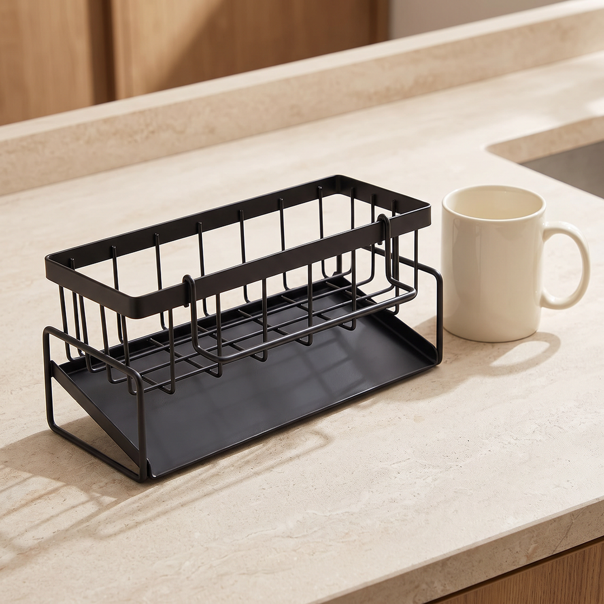 The black sink caddy beside a cream mug on a stone worktop for size