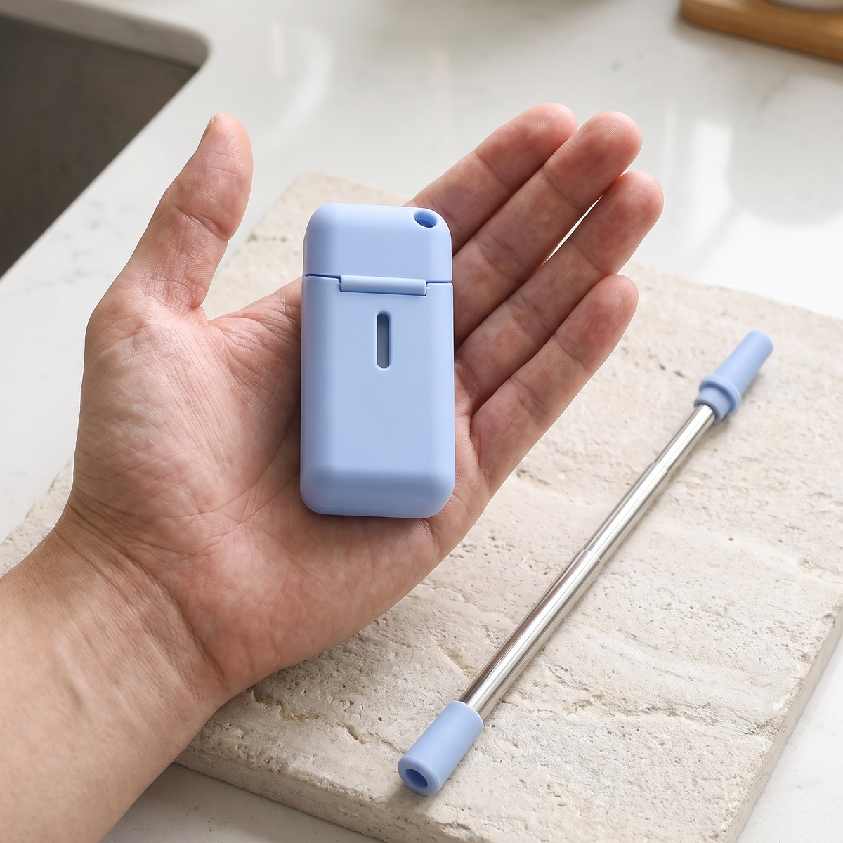 Closed blue case resting in an open palm beside the extended straw