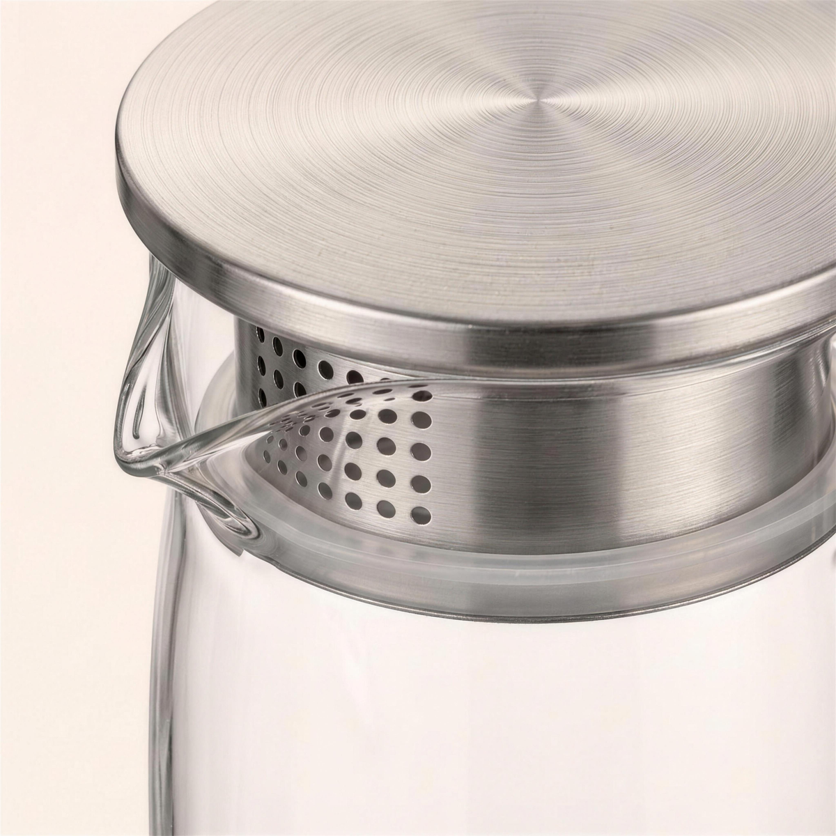 Close-up of the brushed steel lid and its perforated filter above the glass spout