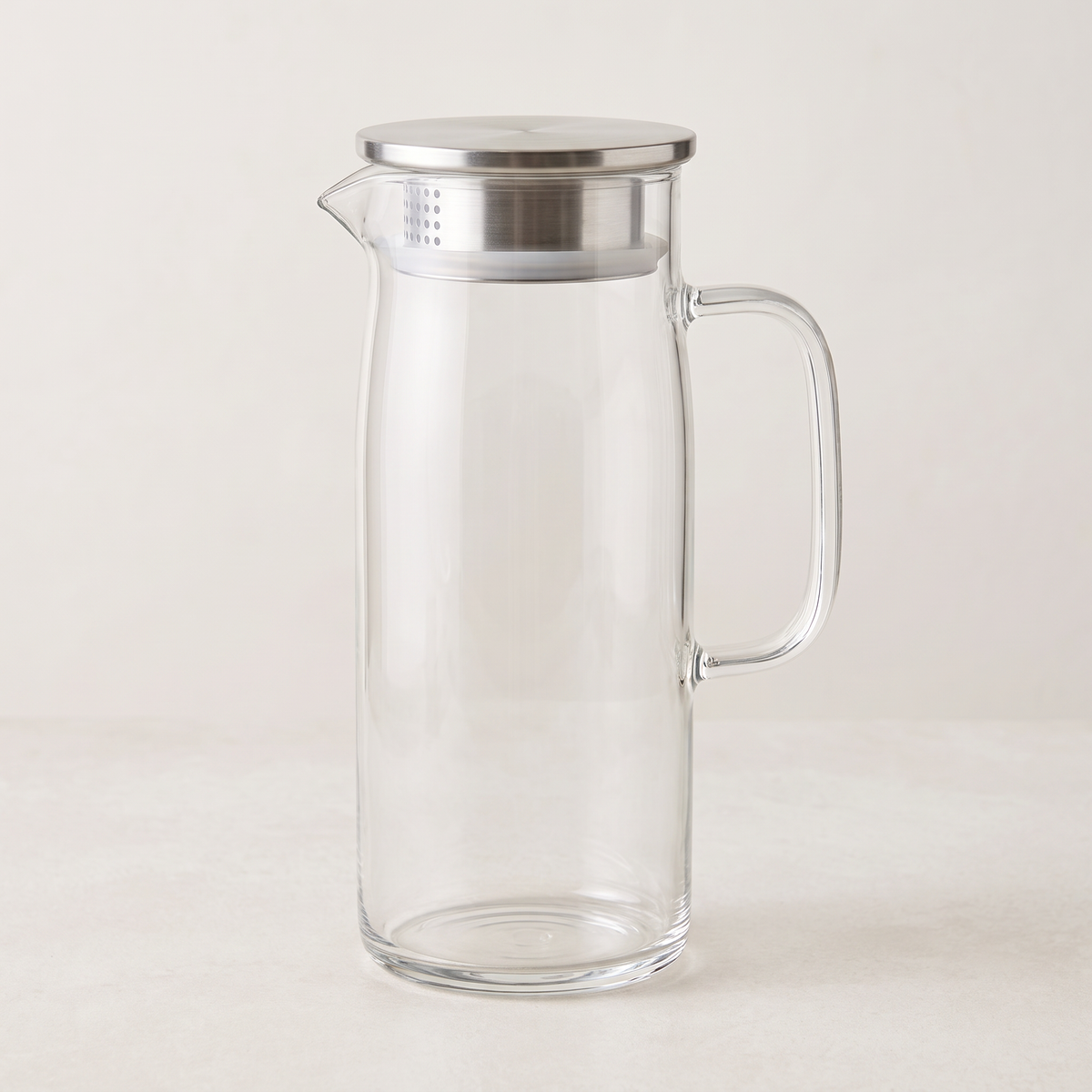 Empty clear glass jug with a straight body, glass handle and stainless-steel lid