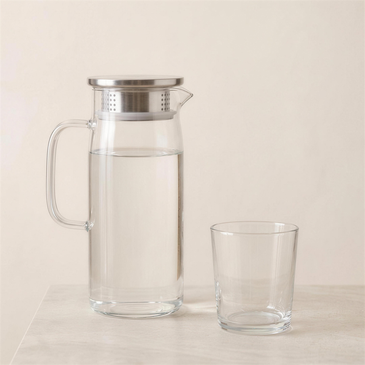 The pitcher half filled with water beside a plain drinking glass for size