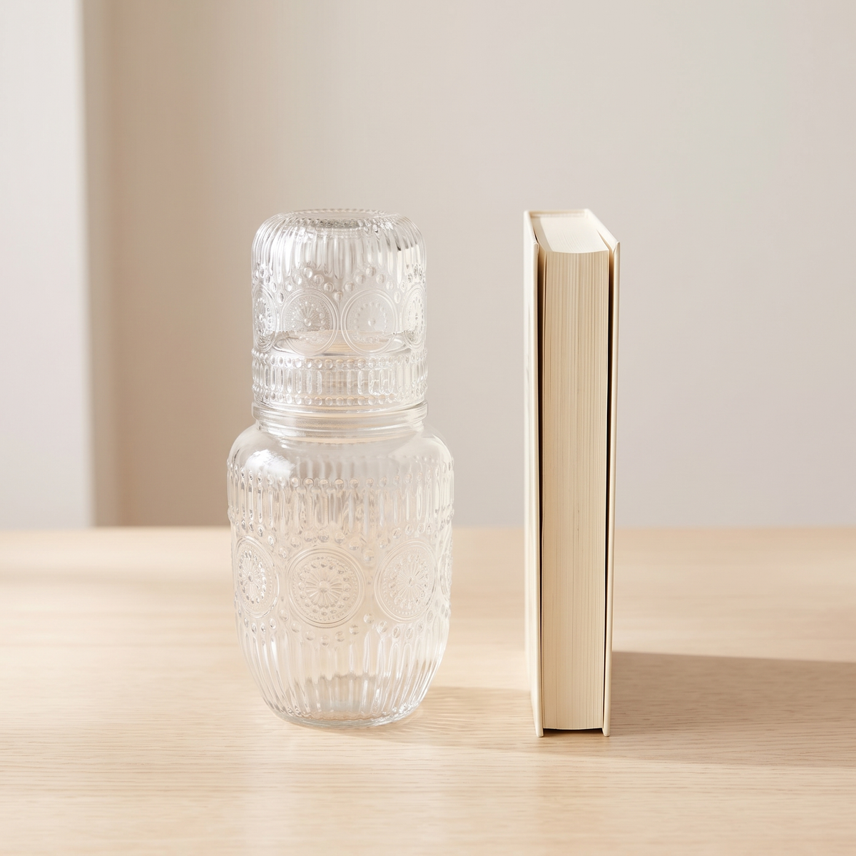 The carafe and glass set standing beside a hardback book for size