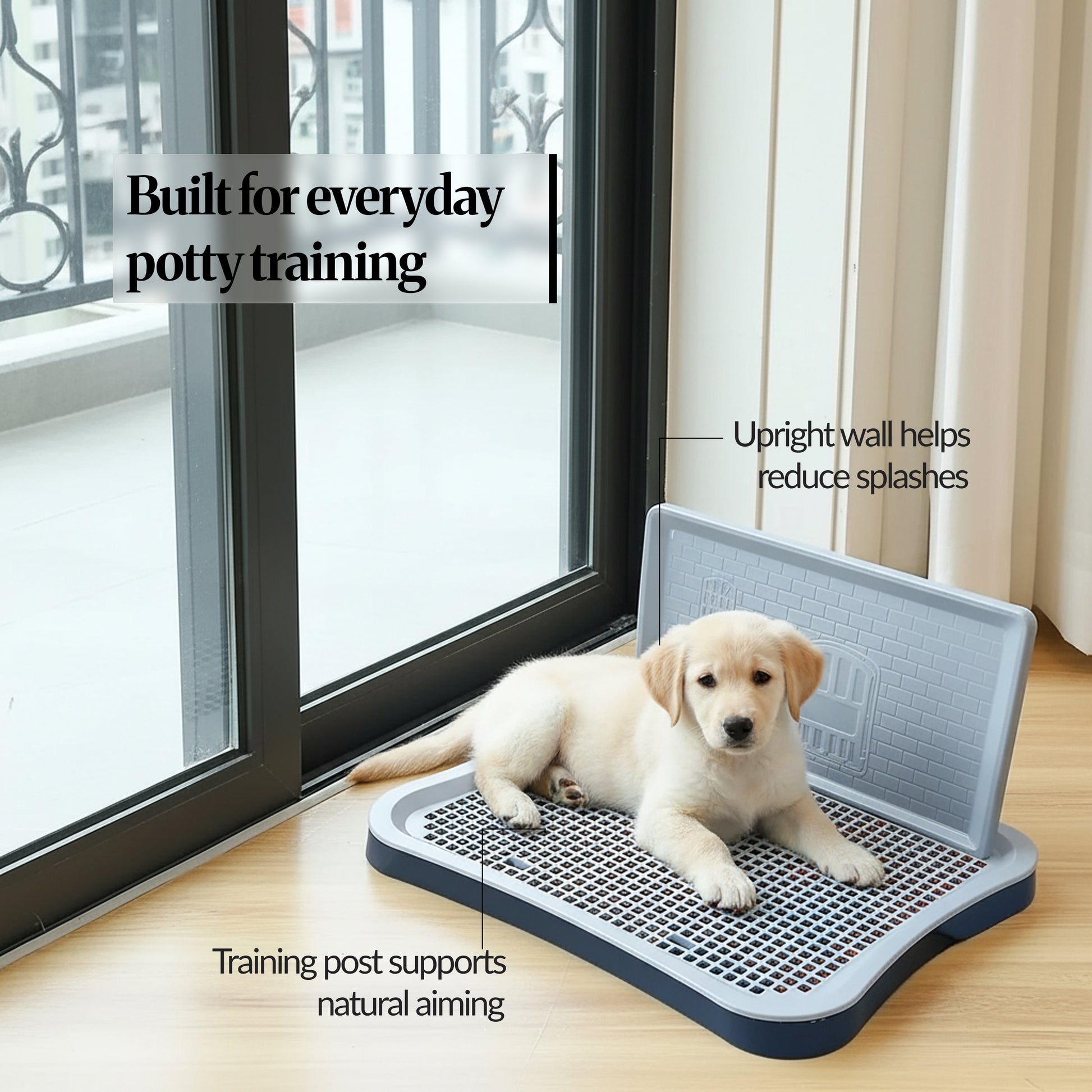 Puppy lying on an indoor dog potty tray by a glass door, highlighting the upright wall to reduce splashes and the training post for natural aiming.