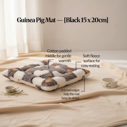 Black guinea pig bed mat (15×20cm) soft fleece mat with cotton padding and stitched edging, photographed on a warm neutral surface with feature callouts