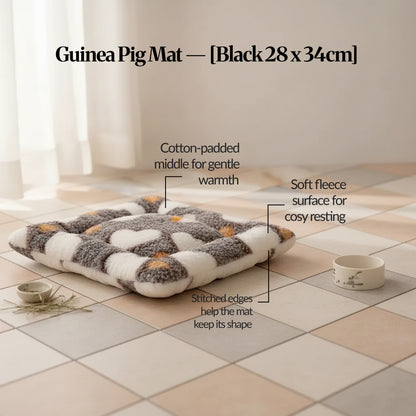 Black guinea pig bed mat (28×34cm) plush fleece, cotton-padded mat with stitched edges, shown on tiled floor with feature callouts.