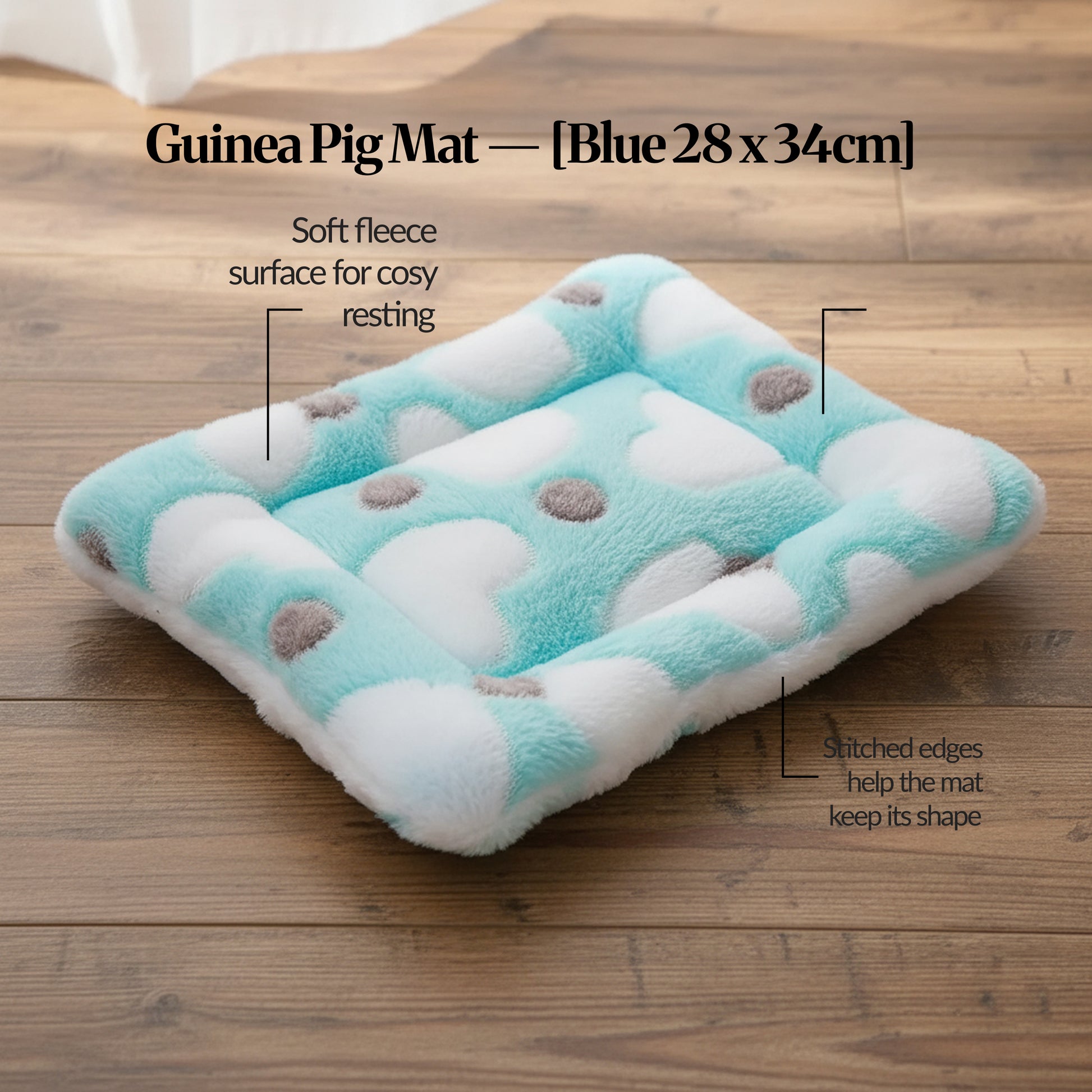 Blue guinea pig bed mat (28×34cm) plush fleece mat with stitched edges for shape, photographed on a wooden floor with feature callouts.