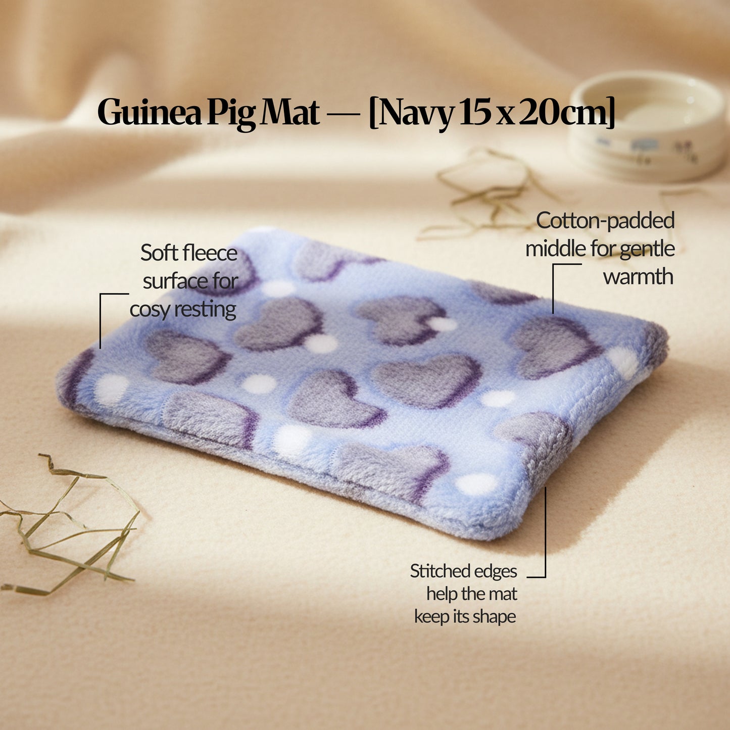 Navy guinea pig bed mat (15×20cm) plush fleece mat with cotton padding and stitched edges, photographed on a warm neutral surface with feature callouts.