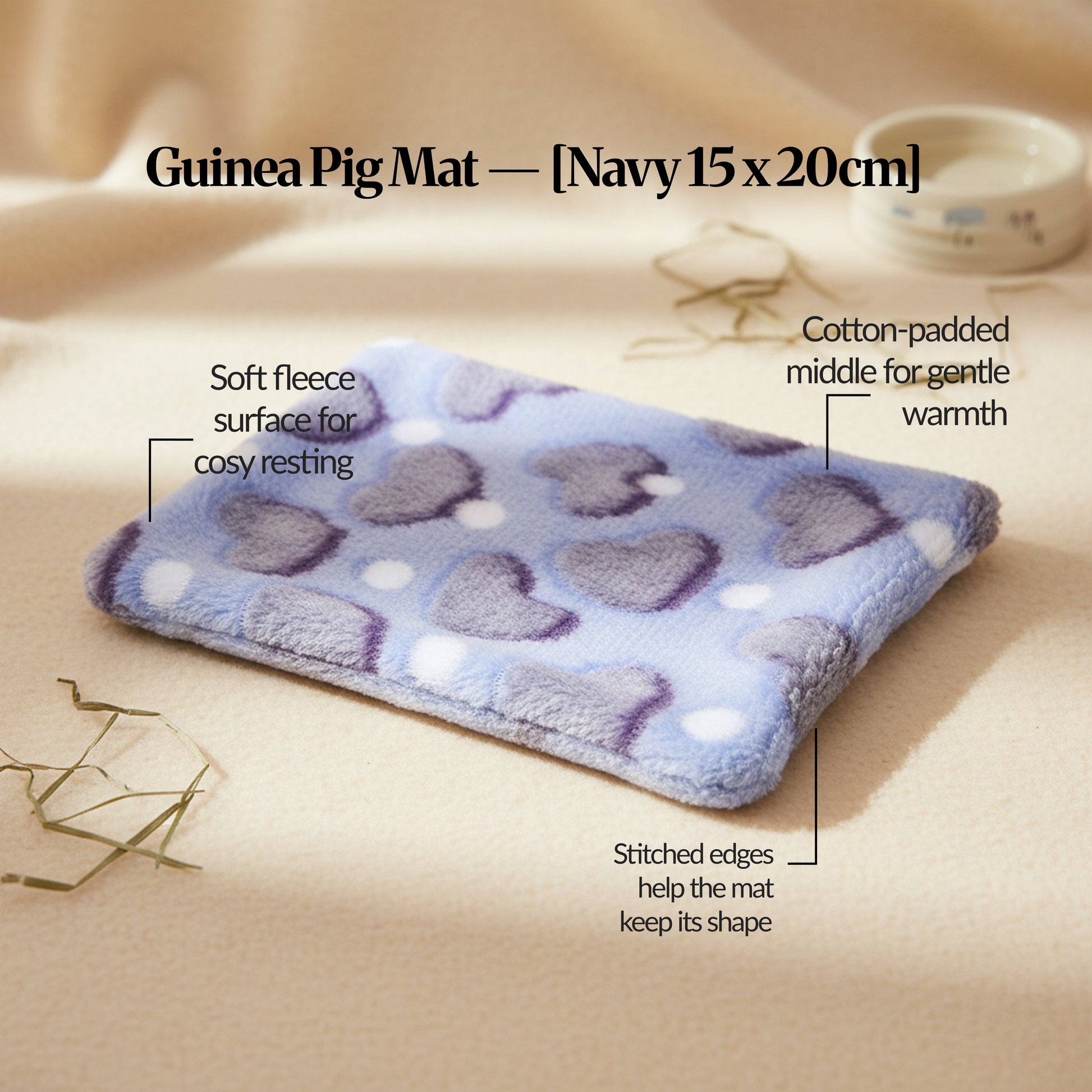 Navy guinea pig bed mat (15×20cm) plush fleece mat with cotton padding and stitched edges, photographed on a warm neutral surface with feature callouts.