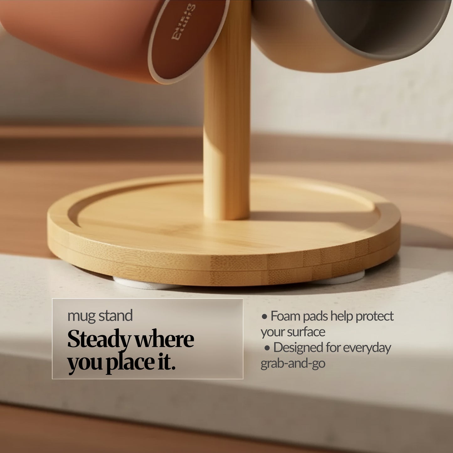 Close-up of the bamboo mug stand base with foam pads underneath for surface protection; mugs hanging above; overlay reads “Steady where you place it.”