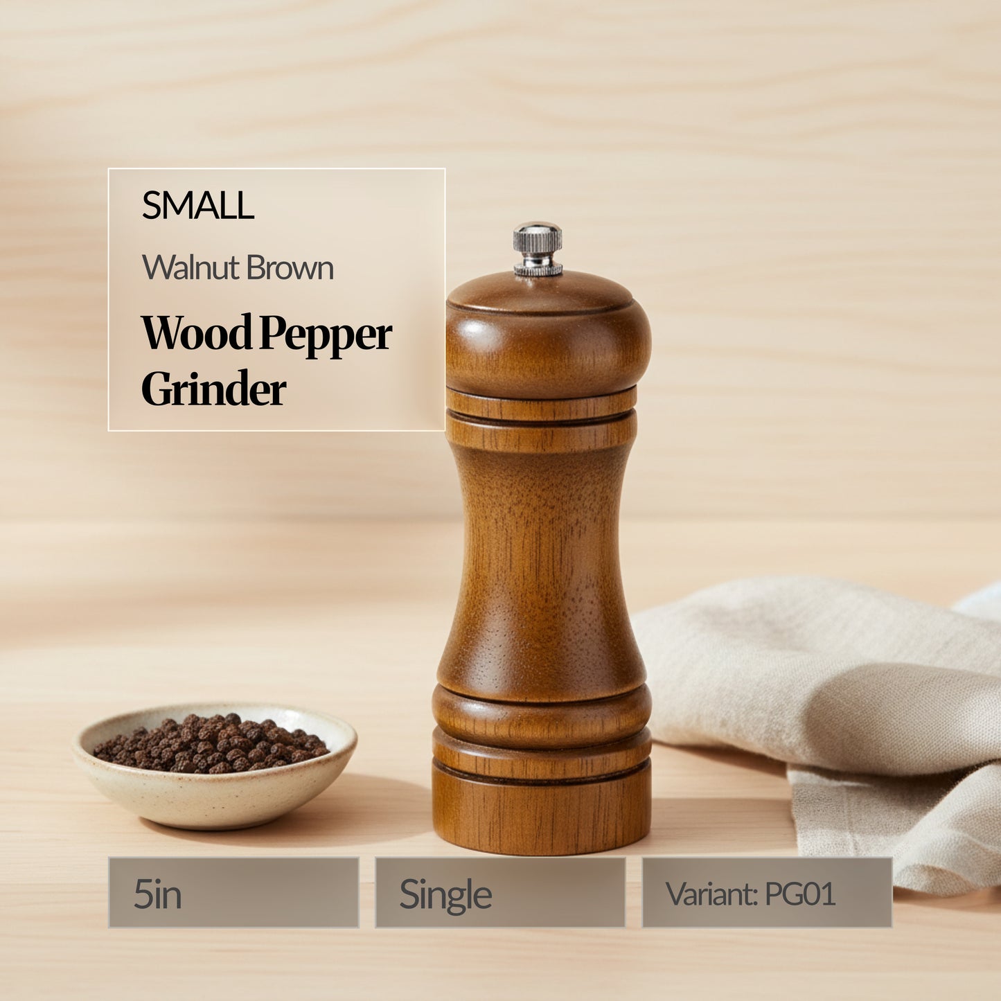 Small walnut brown wood pepper grinder (single, 5in) on a wooden surface with a bowl of peppercorns and linen cloth; text overlay shows “Variant: PG01”.