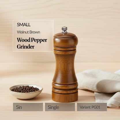 Small walnut brown wood pepper grinder (single, 5in) on a wooden surface with a bowl of peppercorns and linen cloth; text overlay shows “Variant: PG01”.