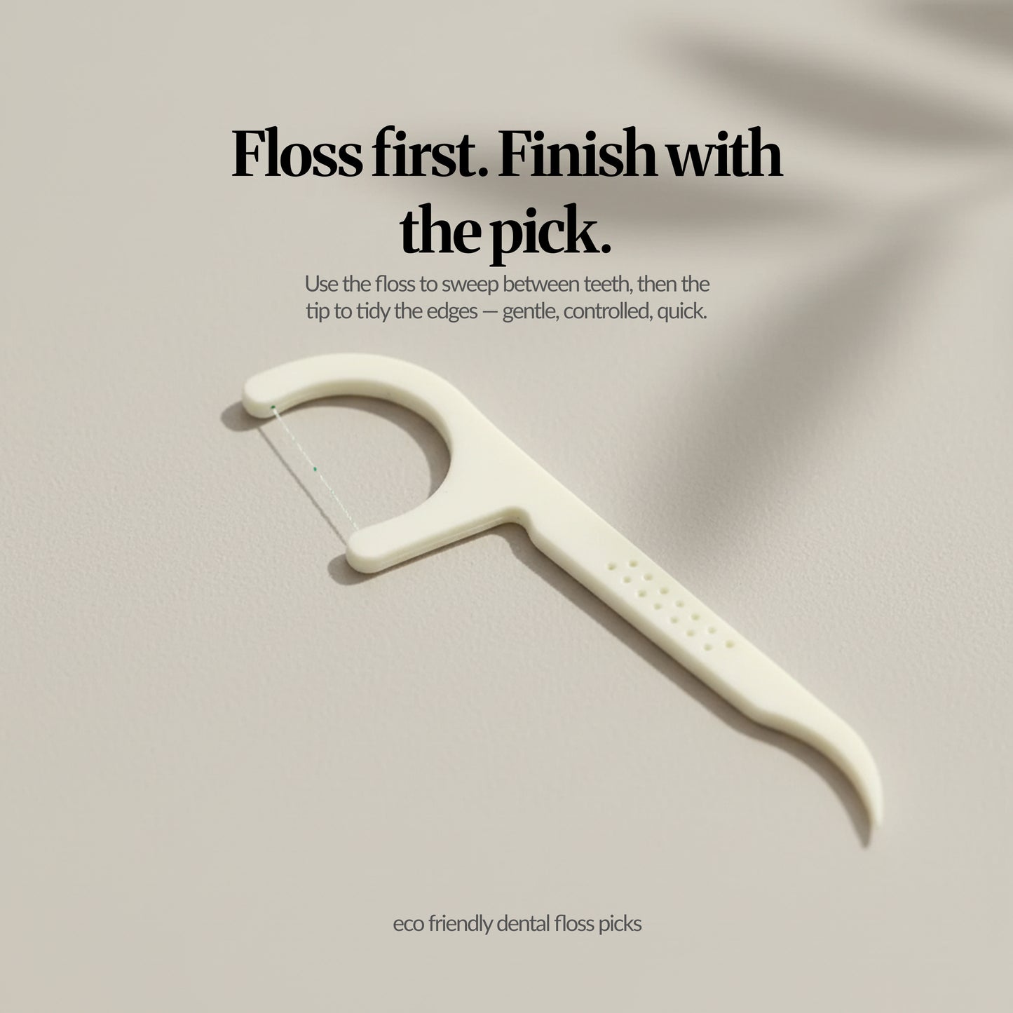 Close-up of a single mint dental floss pick showing floss thread and pointed tip, with text ‘Floss first. Finish with the pick.