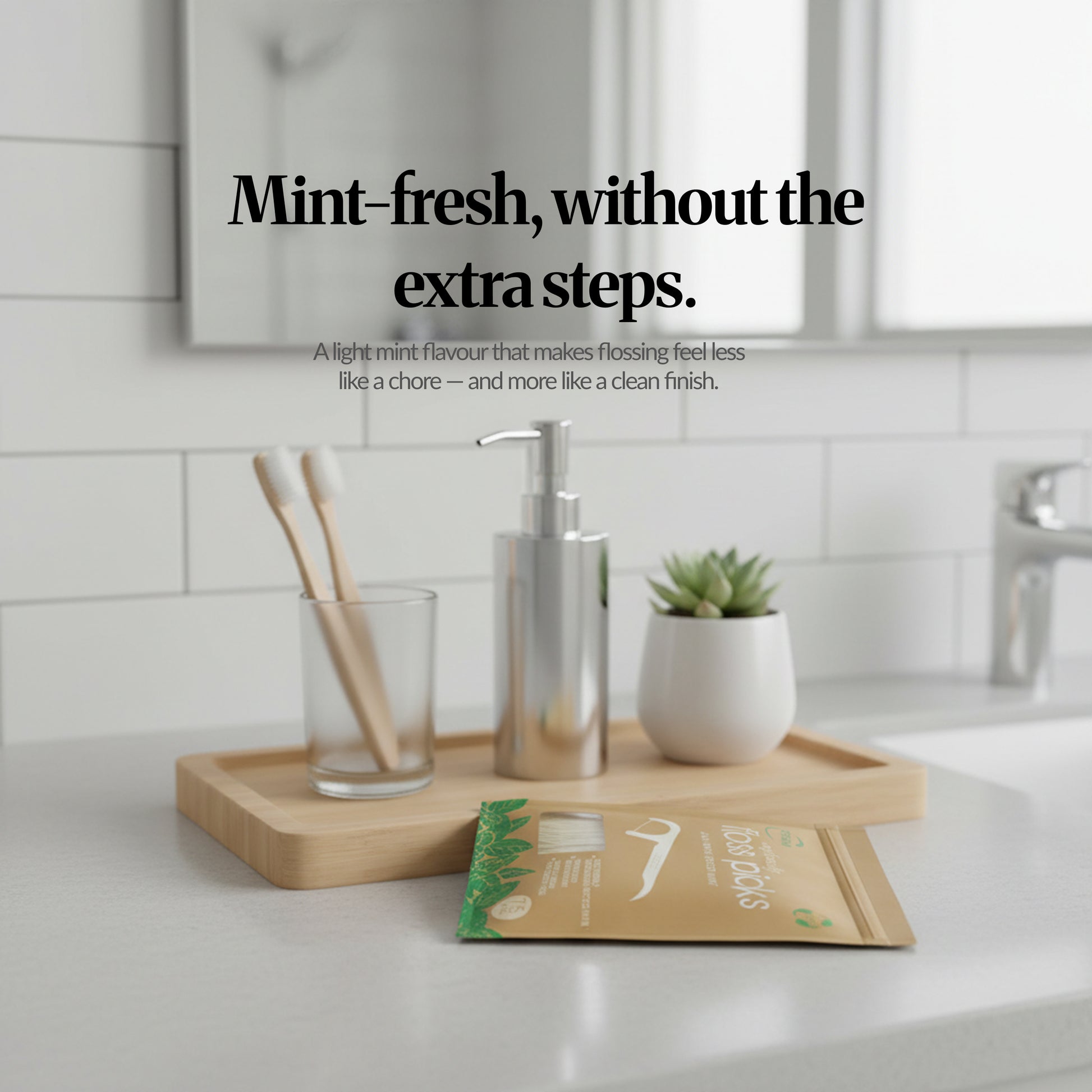 Bathroom countertop scene with bamboo tray and toiletries, featuring the mint floss picks pack and headline ‘Mint-fresh, without the extra steps.’