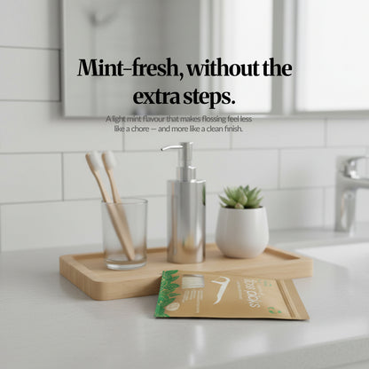 Bathroom countertop scene with bamboo tray and toiletries, featuring the mint floss picks pack and headline ‘Mint-fresh, without the extra steps.’