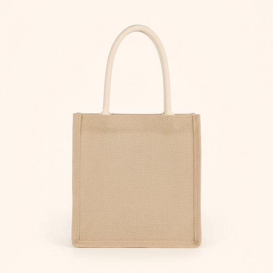 Medium woven tote bag with two cream rope handles, standing upright on cream