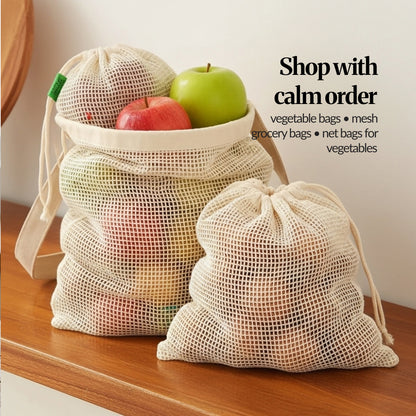 Stacked cotton mesh grocery bags filled with apples on a wooden counter, showing how the reusable produce bags hold fruit neatly.