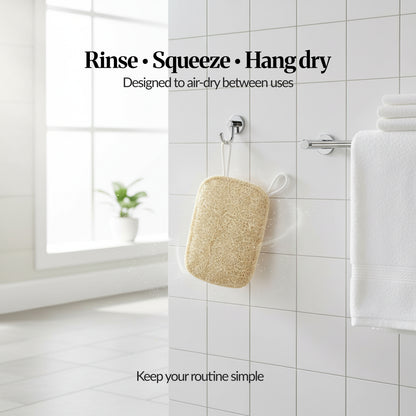 Loofah sponge hanging from a bathroom hook on white tiled wall, showing “Rinse • Squeeze • Hang dry” air-dry routine between uses.