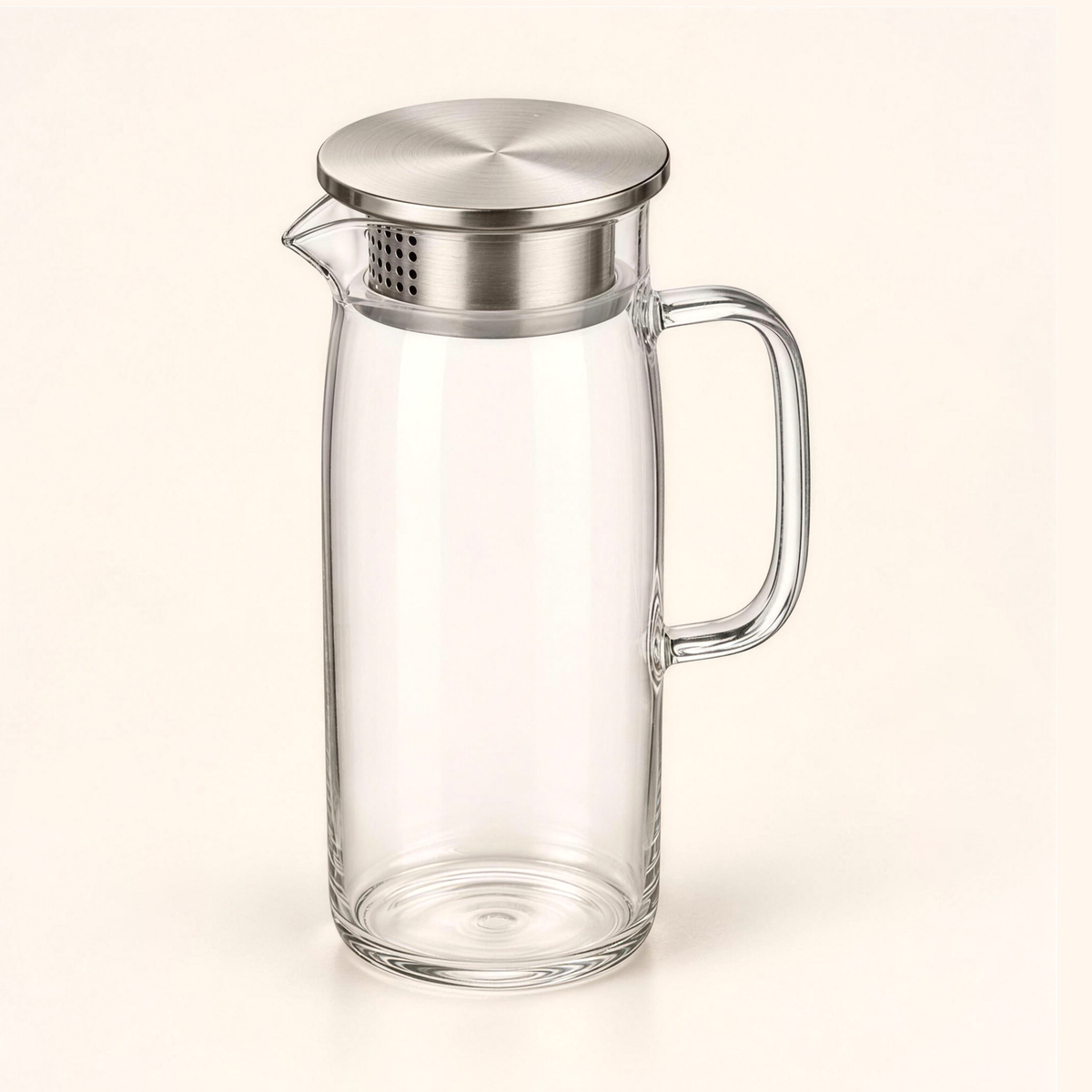 The 1 litre glass water pitcher with its perforated stainless-steel filter lid, on cream
