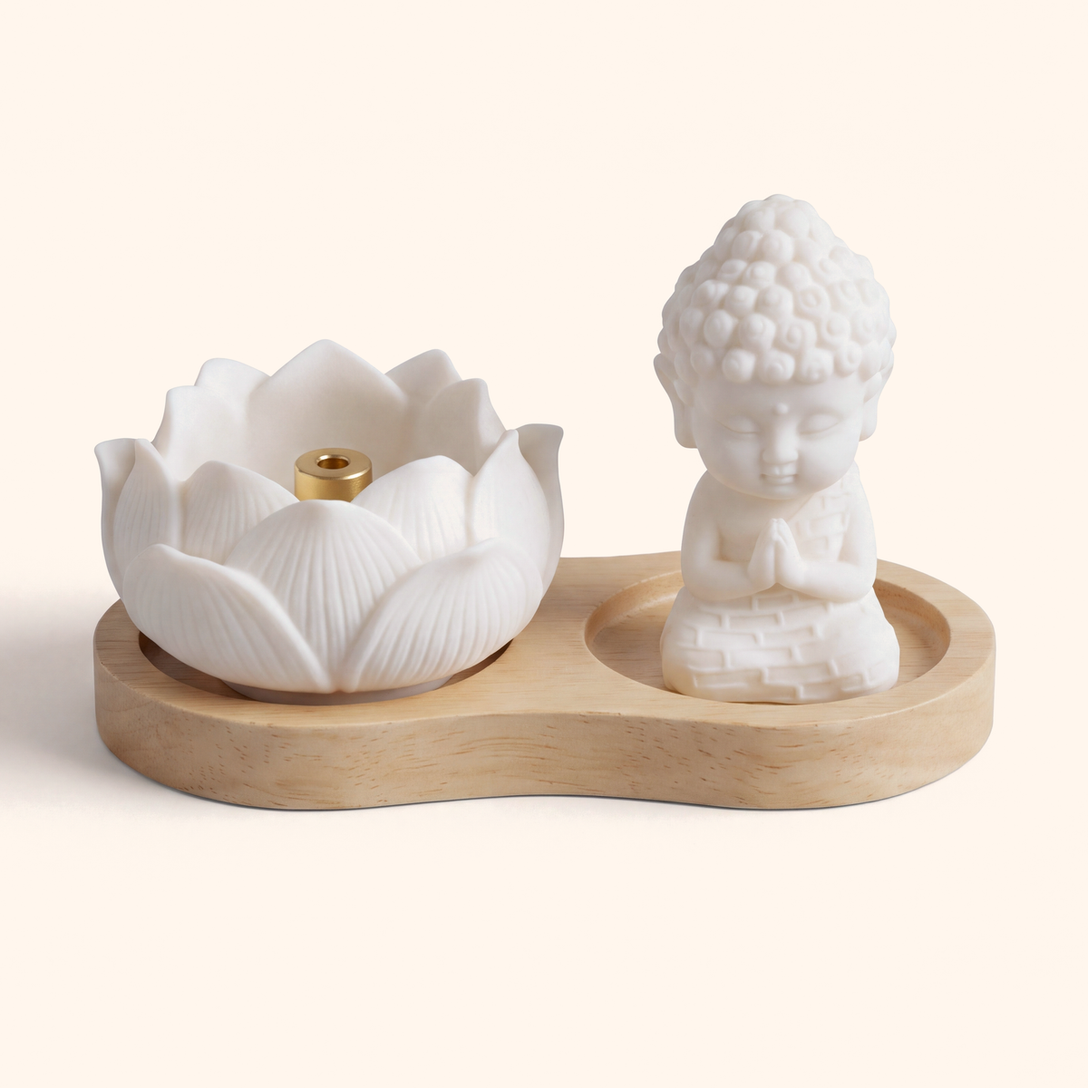 White ceramic lotus incense holder and small monk figure on a light wood tray, on cream