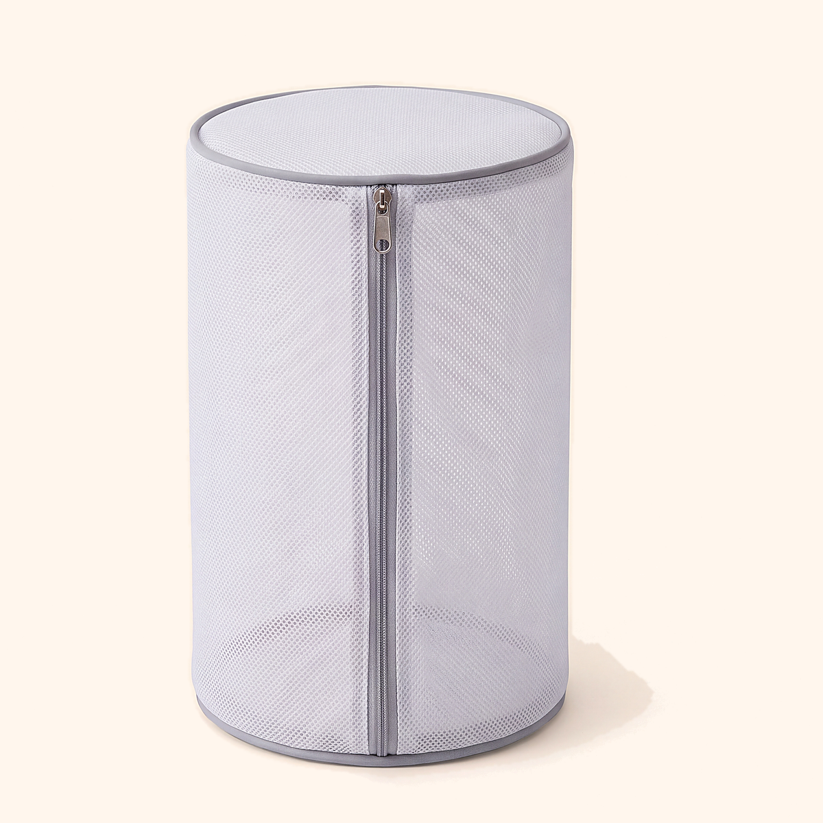 Round white mesh shoe washing bag standing upright with a grey full-length zip