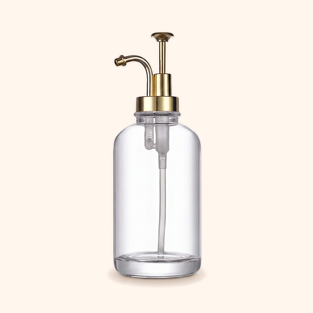Clear glass pump dispenser with a curved gold-tone pump, on cream