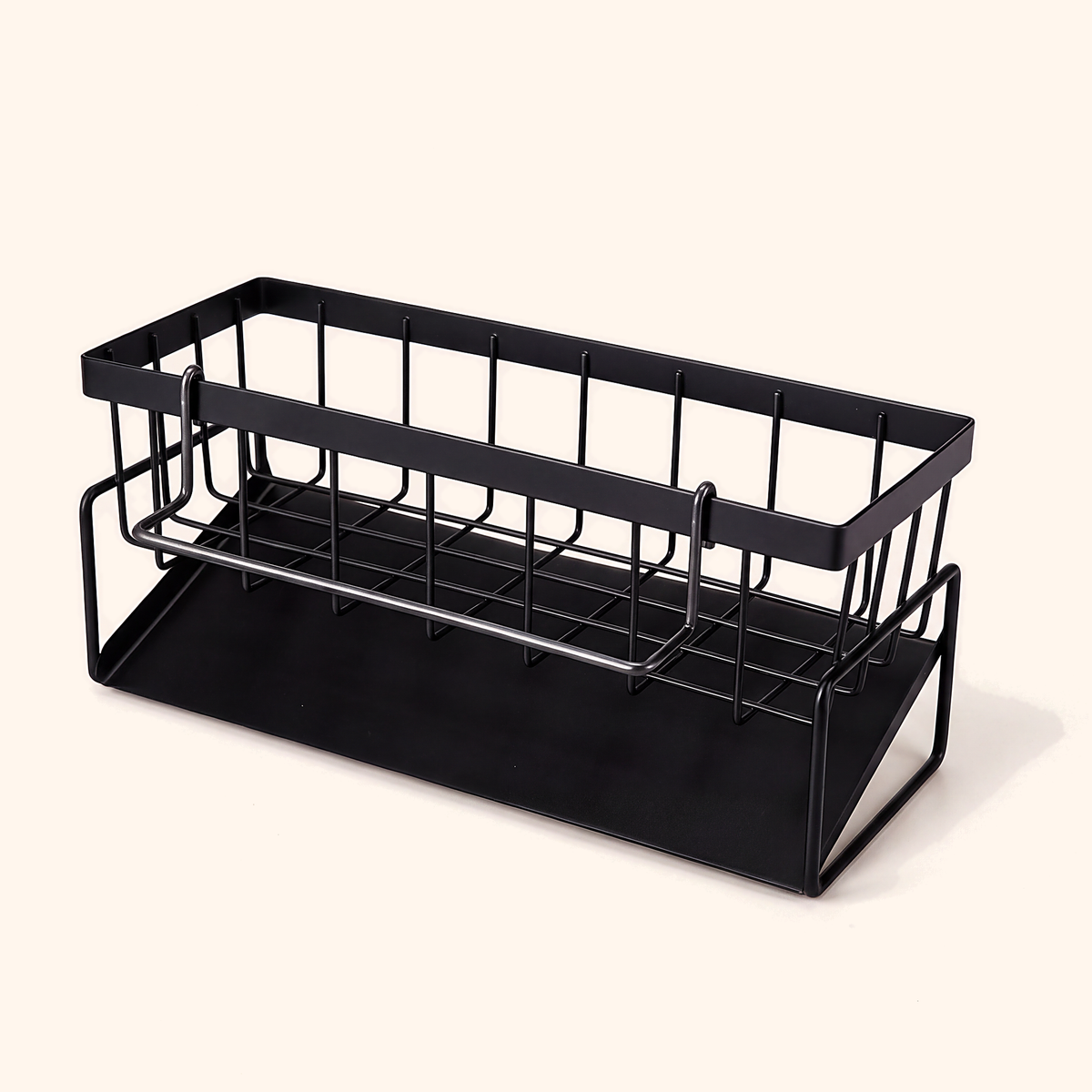 Black metal kitchen sink caddy with an open wire basket above a solid tray, on cream
