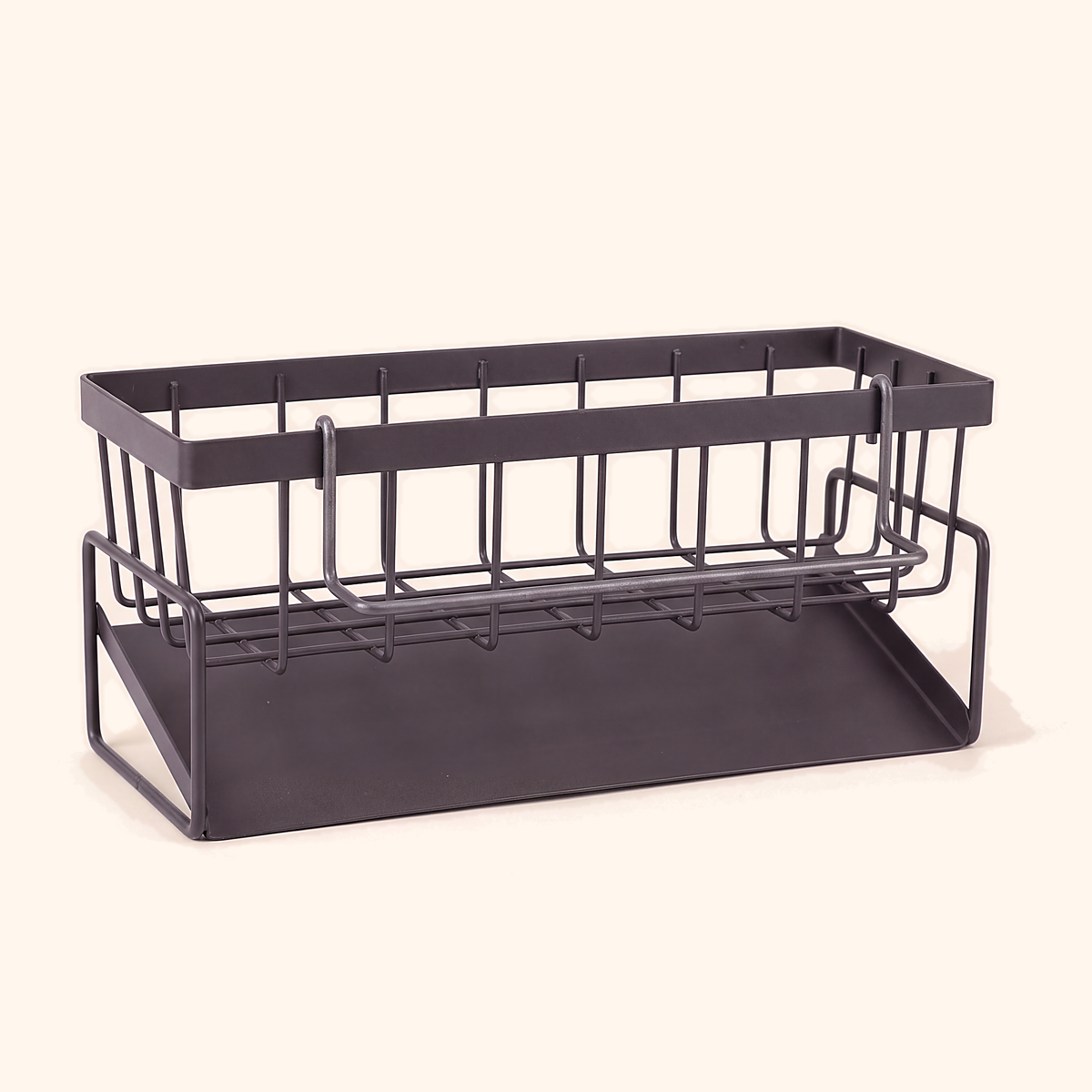 Grey metal sink caddy with an open wire basket and solid base tray, on a cream background